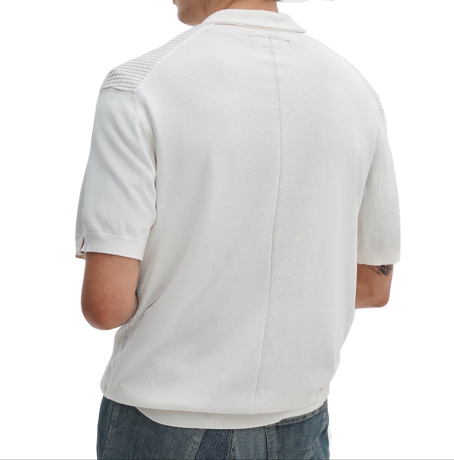 A man is seen from behind wearing a white Rag & Bone Saxon Silk-Cotton Polo Shirt with textured shoulder panels and blue jeans, set against a plain white background.