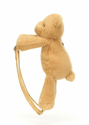 A tan Jellycat Smudge Bear Backpack by Jellycat, shaped like a teddy bear and shown in profile, features two beige adjustable straps visible against a white background.