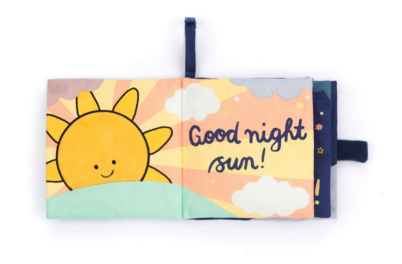 A Jellycat Hello Moon Fabric Book open to a colorful page showing a smiling sun with the text "Good night sun!" in a playful font. Perfect for little hands, this interactive fabric book from Jellycat sparks joy and curiosity.