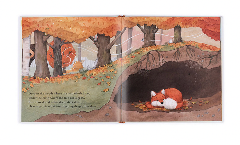 A two-page illustration in a children's book shows a fox sleeping underground in a burrow surrounded by autumn trees. The text on the left page describes the fox dozing off and feeling warm, making it an ideal bedtime story. This giftable hardback edition of **Jellycat Warm in the Storm Book** by **Jellycat** is perfect for young readers.