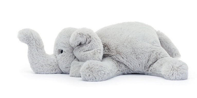 A Jellycat Wanderlust plush toy elephant, affectionately named Wanderlust Elly, lying down on its side with its trunk curled slightly and its legs extended. The toy is light grey and has a soft, fluffy texture that's perfect for any traveller's friend.