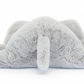 A grey stuffed toy resembling an elephant, fittingly named Jellycat Wanderlust, is lying face-down with its legs splayed outwards.