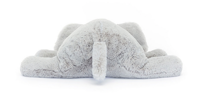 A grey stuffed toy resembling an elephant, fittingly named Jellycat Wanderlust, is lying face-down with its legs splayed outwards.