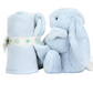 A Jellycat Bashful Blue Bunny Soother, made from recycled fibers, is seated beside a rolled-up matching light blue plush blanket tied with a ribbon labeled "Baby Blanket." The bunny has long ears and a white, fluffy tail, making it the perfect newborn gift.