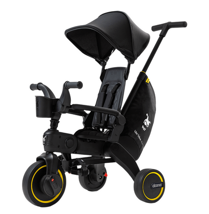 The DOONA Liki Trike - Midnight Edition by Doona is a sleek, foldable, three-wheeled stroller alternative with a canopy, adjustable handles, and yellow-accented wheels. This 5-in-1 compact folding trike also features a storage bag and prominently displays the logo on the side.