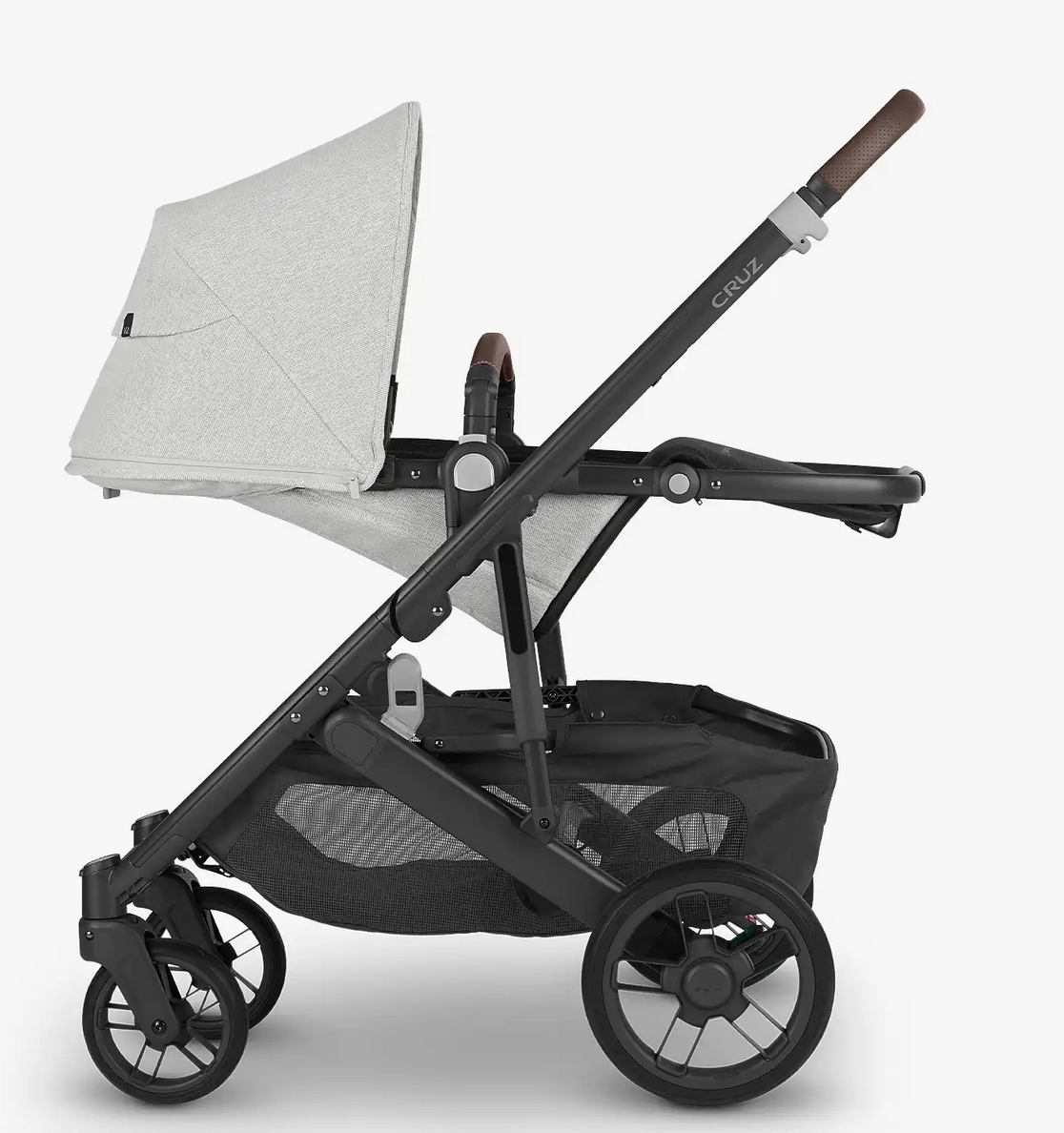 Side view of the UPPAbaby Cruz V2 Stroller in gray with a black frame, an adjustable handlebar, and brown accents. The stroller, by UPPAbaby, features four wheels, a storage basket underneath, and a comfortable toddler seat.