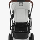 A rear view of the UPPAbaby Cruz V2 Stroller in gray showcases its adjustable handlebar, brown handlebars, large black wheels, and a storage compartment underneath.