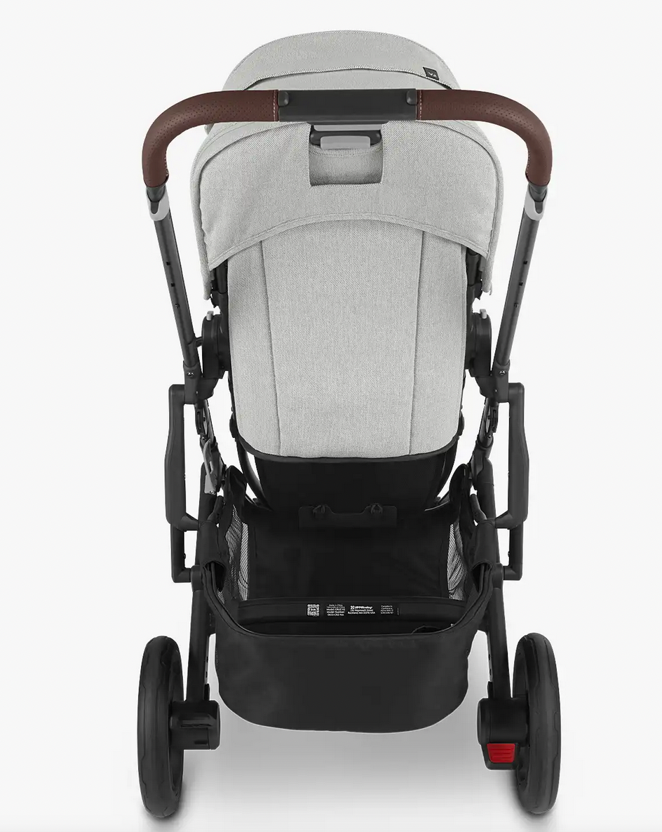 A rear view of the UPPAbaby Cruz V2 Stroller in gray showcases its adjustable handlebar, brown handlebars, large black wheels, and a storage compartment underneath.