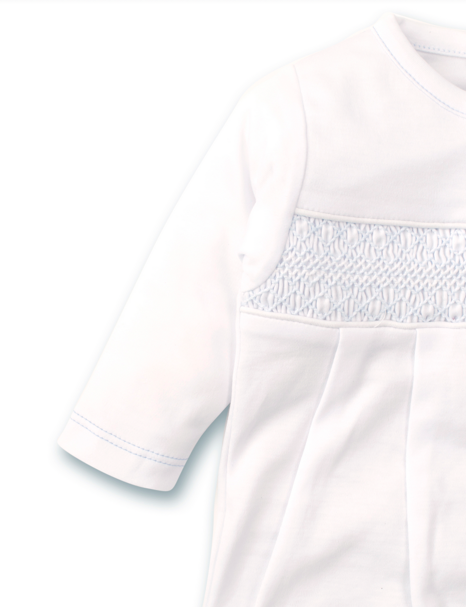 A close-up of the Kissy Kissy Footie with Hand Smocking, crafted from soft pima cotton, showcasing intricate smocking on the chest and pleats below, complemented by a convenient snap closure for easy dressing.