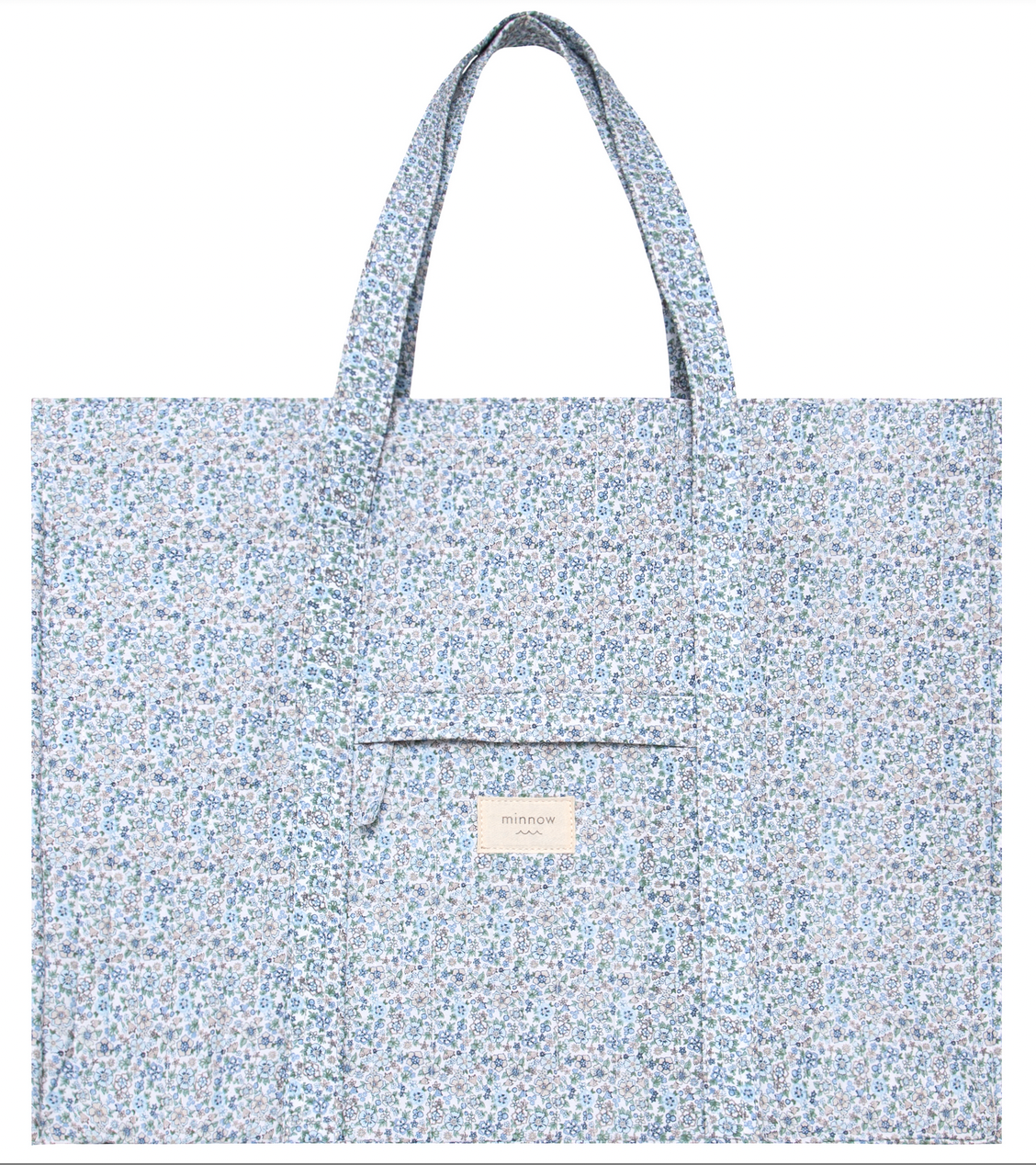 The Minnow Overnighter Tote by Minnow is a blue, floral-patterned, quilted fabric tote bag featuring two long straps and a square front pocket. A small label reading "minnow" is attached to the front pocket, adding a charming touch to your collection. Additionally, its spacious interior ensures you can carry all your essentials with ease.