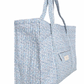 The Minnow Overnighter Tote by Minnow features a blue and white floral pattern, long handles, a front pocket, and a spacious interior crafted from quilted fabric.