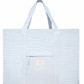 The Minnow Overnighter Tote by Minnow is a large blue striped quilted fabric bag featuring two handles, a front pocket with a small branded tag, and a spacious interior.