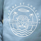 Close-up of the Tartine et Chocolat Camper Van Sweatshirt in blue, showcasing a logo with a van, palm trees, waves, and a surfboard, encircled by the text "Tartine et Chocolat" and "Since 1977." Perfect for your baby boy this winter.