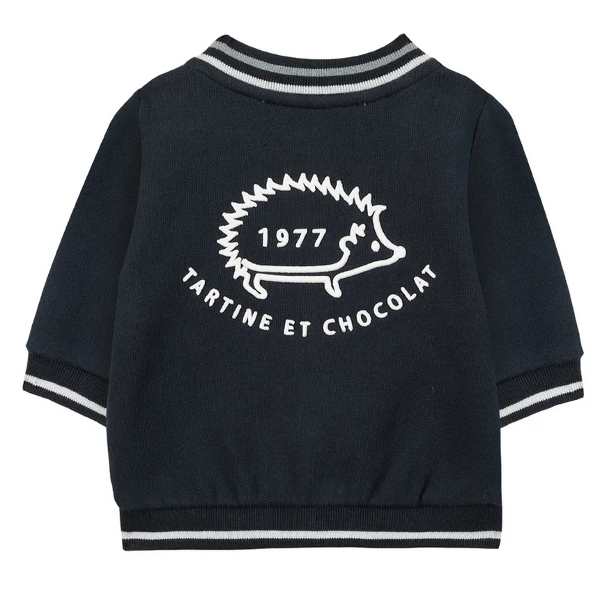 A navy blue Tartine et Chocolat Outfit Jogging Suit jacket featuring white stripes on the sleeves and collar. The back showcases a white hedgehog graphic with the text "1977" above it and "Tartine et Chocolat" below, making it perfect for your baby boy.