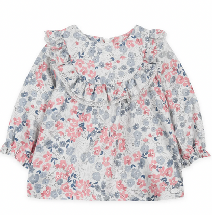 The Tartine et Chocolat Raspberry Printed Floral Blouse by Tartine et Chocolat is a long-sleeve children's dress with a white base, adorned with raspberry tones in its flowery pattern. It features ruffled detailing on the chest and elastic cuffs on the sleeves.