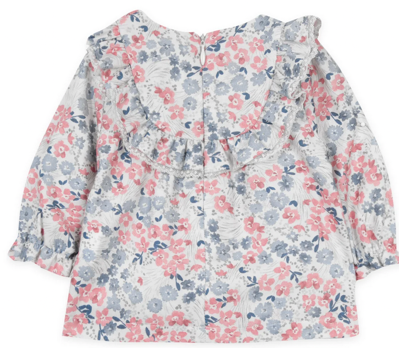 The Tartine et Chocolat Raspberry Printed Floral Blouse from Tartine et Chocolat is a charming long-sleeve children's dress with a delightful flowery pattern in shades of pink, blue, and white. It features frills around the neckline and a convenient button closure at the back. The enchanting design is accented with raspberry tones, adding an extra touch of sweetness.