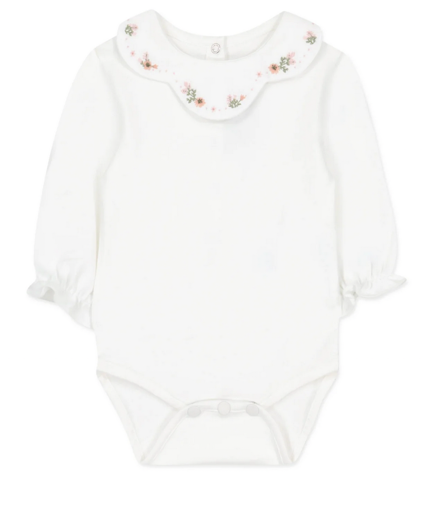 A long-sleeved white baby onesie with an embroidered flower collar and snap buttons at the bottom from Tartine et Chocolat.