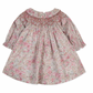 The Tartine et Chocolat Fabric Liberty Pink Dress from Tartine et Chocolat features a floral-patterned, long-sleeve design with smocked detailing on the chest and a round neckline. The light pink fabric is adorned with small multicolored flowers, reminiscent of Print Liberty.