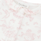 Close-up of the Tartine et Chocolat Pale Pink Toile Pyjama featuring a charming white and pink floral-patterned fabric with a Peter Pan collar. The soft and comfortable material boasts a label reading "Tartine et Chocolat," with pale pink hues enhancing its delightful design.