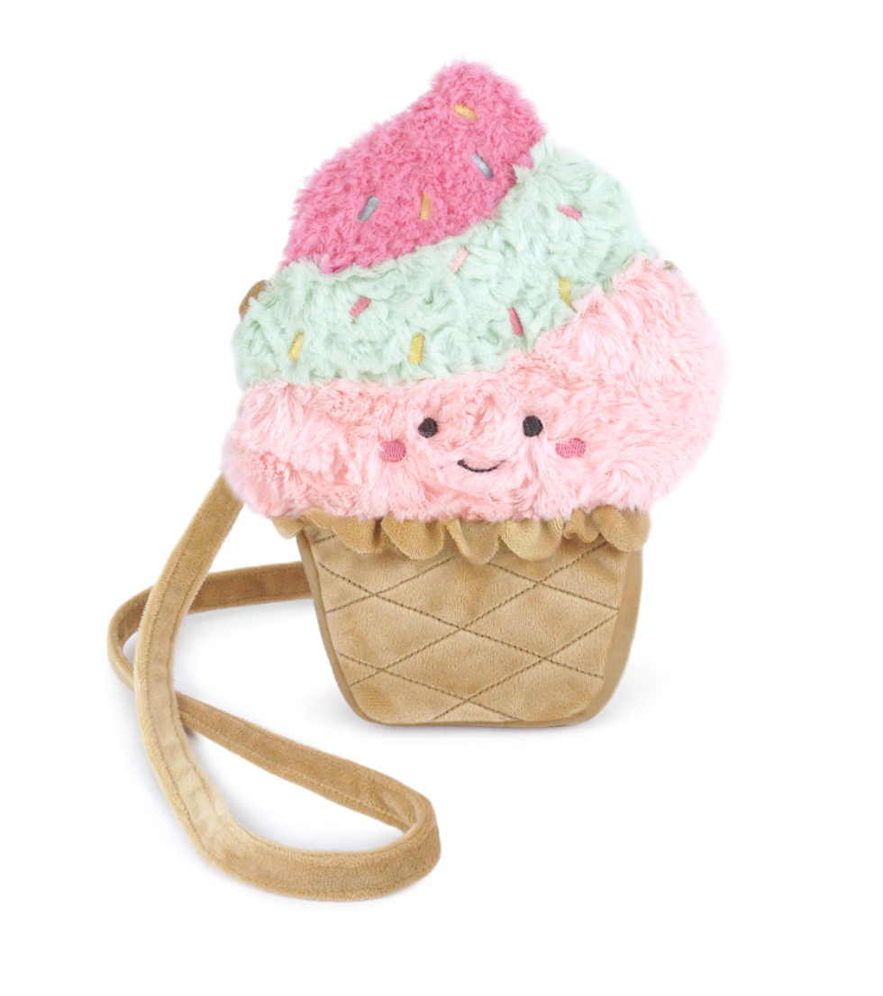 The Mon Ami Ice Cream Purse is a plush crossbody bag shaped like an ice cream cone, featuring cheerful pink and mint green scoops with a smiling face, sprinkle accents, and a tan strap—making it the perfect novelty handbag for kids or a playful ice cream-themed accessory.
