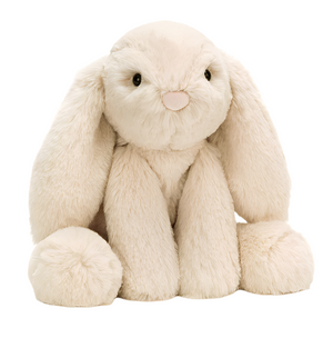 The Jellycat Smudge Rabbit Medium is a cream-colored plush with long floppy ears, round paws, and a pink nose, sitting upright—an adorable baby gift that faces forward.