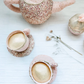 The Mon Ami Floral Stuffed Toy Tea Set, featuring two matching teacups and a sugar bowl, is displayed on a white textured surface with dried flowers beside it.