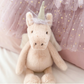 The MON AMI Luna Unicorn Fairy, a charming plush from the Mon Ami brand, is set against a backdrop of pink starry fabric, making it a perfect and delightful gift for toddlers.