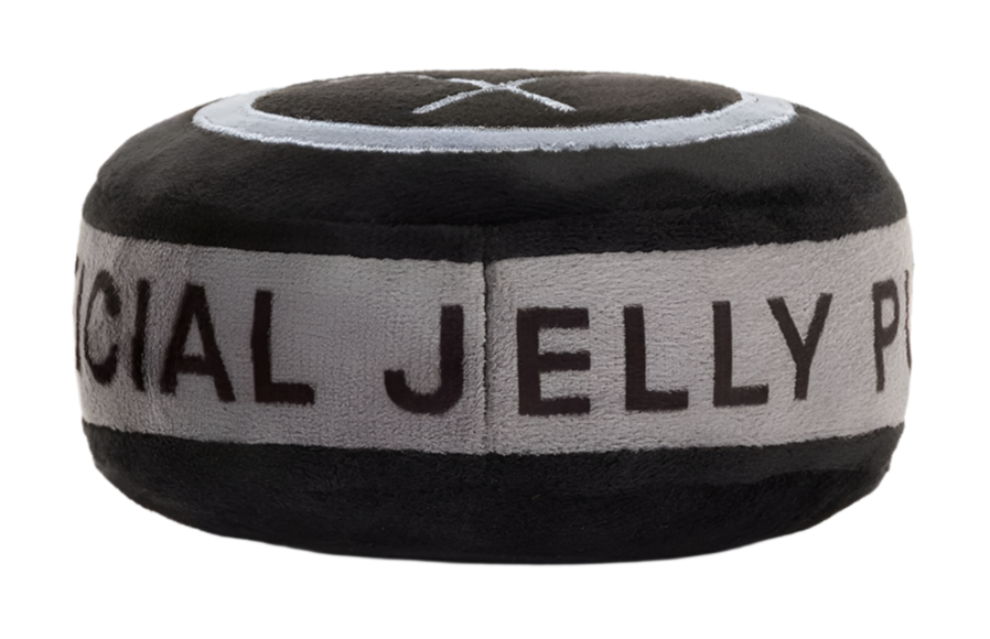 The Amuseables Sports Ice Hockey Puck by Jellycat is a round, plush toy resembling a black and gray puck with "OFFICIAL JELLY PUCK" embroidered on its side, featuring embroidered hockey sticks and faux-suede skates, perfect for sports enthusiasts.