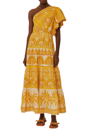 Person wearing the Farm Rio Ainika Tapestry Yellow One Shoulder Maxi Dress, an ankle-length dress with a yellow and white floral pattern, featuring a ruffle neckline and tiered skirt, paired with flat sandals.