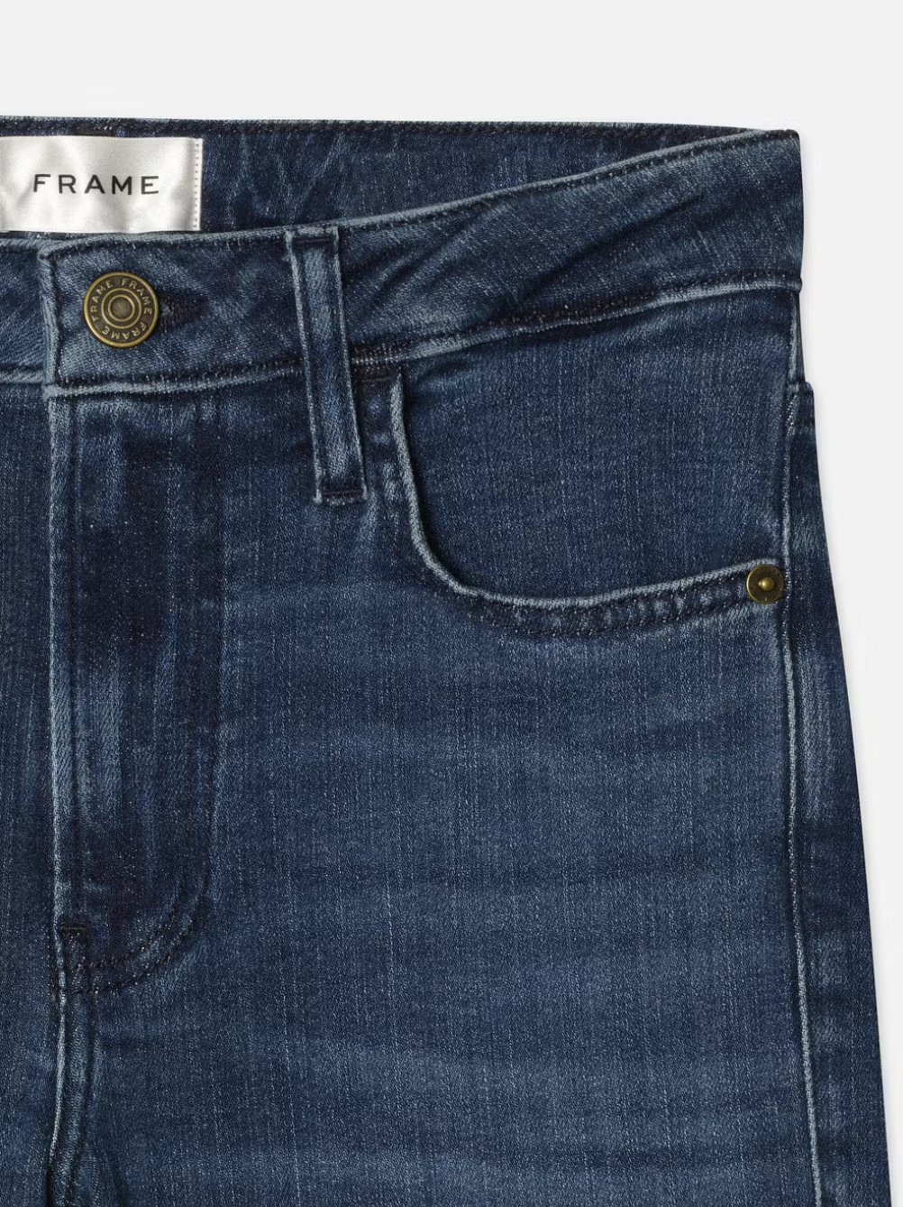 Take a closer look at the Frame Le Crop Mini Boot Cascade, a pair of dark blue denim jeans featuring a high-rise waist and a noticeable metal button. The pocket exudes classic charm, while the "Frame" label assures exceptional quality. Experience both comfort and style with these super stretch denim jeans.