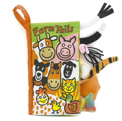 The Jellycat Farm Tails Book by Jellycat is a colorful cloth book with cartoon farm animals on the cover and various textured tails sticking out from the sides. This soft, squishy book is perfect for little hands to explore.