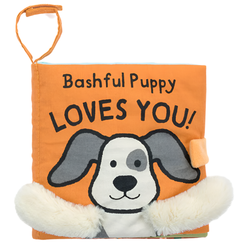 A Jellycat orange cloth baby book cover with a drawing of a dog and the words "Bashful Puppy LOVES YOU!" on it. The Jellycat Bashful Puppy Loves You Book features soft, furry fabric accents.