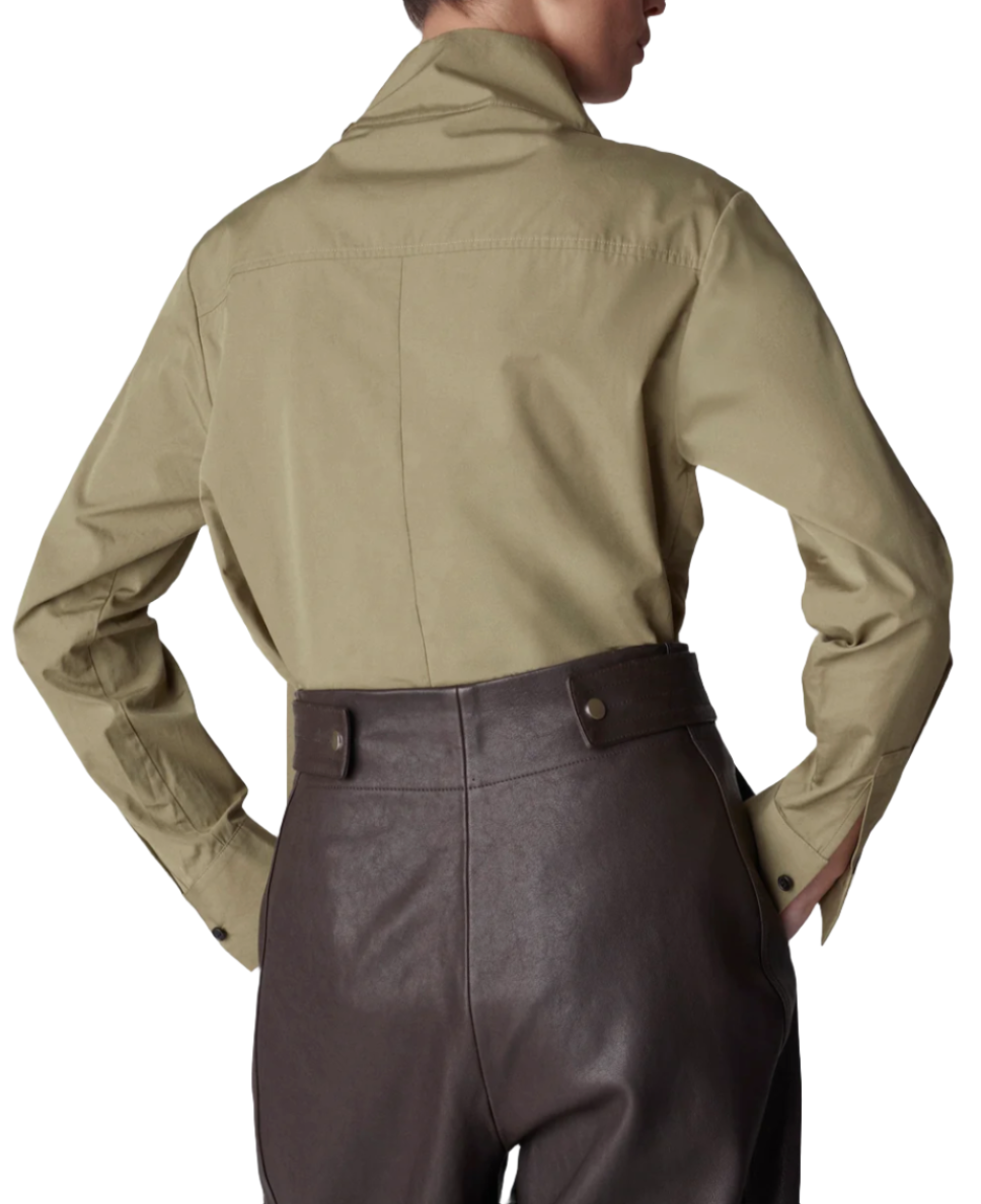 A person is seen from the back wearing the CO Fencer's Fluid Blouse in khaki, which features a subtle flyaway hem, paired with brown high-waisted pants.