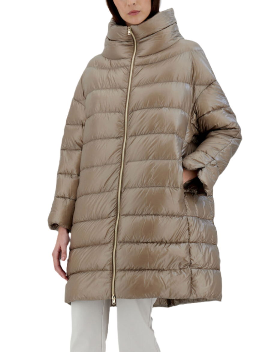 A person wearing the Herno Matilde Coat, an oversized beige down jacket made from ultralight nylon, featuring a high collar and zipper, stands against a plain background.