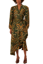 A person wearing a lively Farm Rio Pineapple Ikat Green Long Sleeve Midi Dress, which features long sleeves and an asymmetrical hem with a striking pineapple ikat print, paired with brown shoes. The beaded edges lend an additional touch of elegance to the outfit.