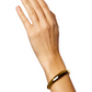 A hand wearing a LIÉ STUDIO Amanda Bracelet made of shiny gold-plated brass from Lie Studio is shown against a white background.