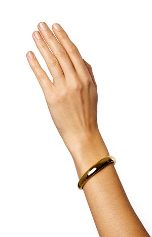 A hand wearing a LIÉ STUDIO Amanda Bracelet made of shiny gold-plated brass from Lie Studio is shown against a white background.