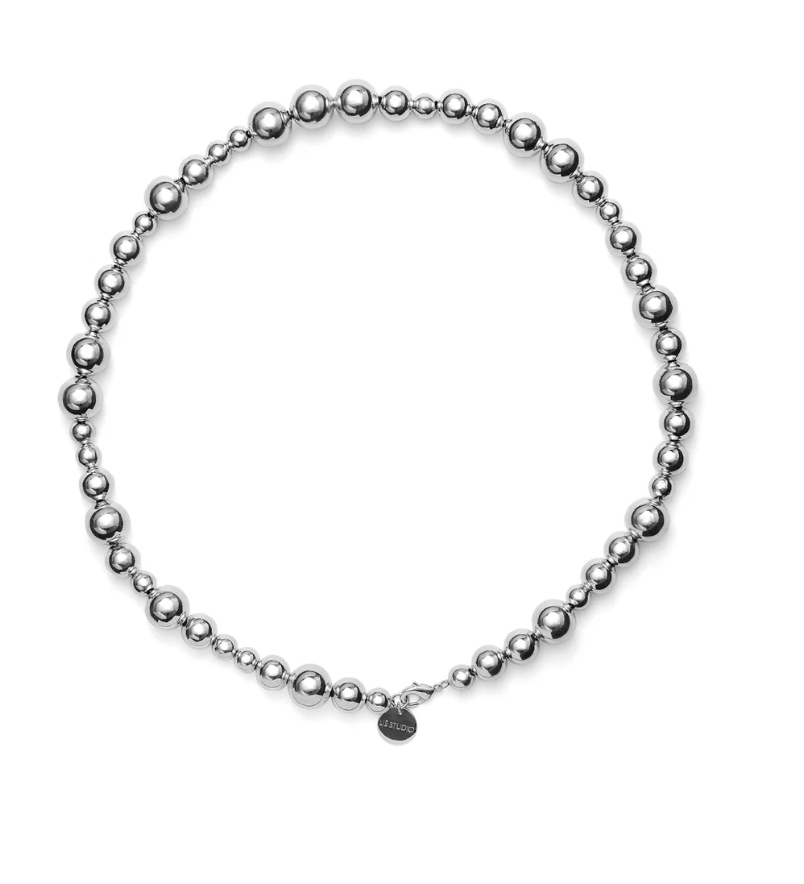 The LIÉ STUDIO Elly Necklace by Lie Studio features silver-plated brass beads with a circular pendant near the clasp.