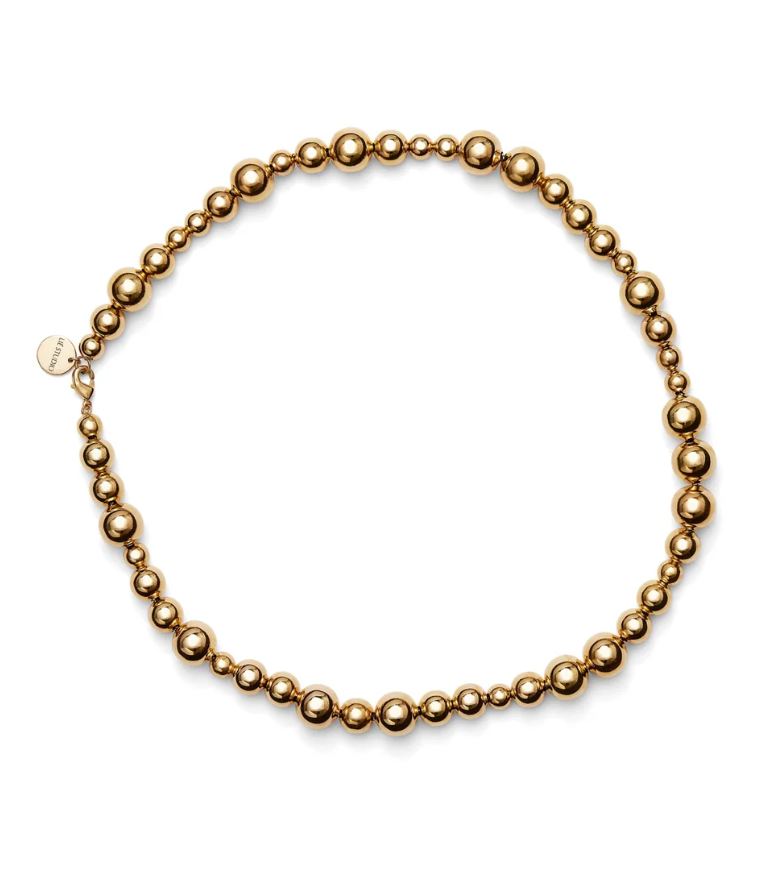 Introducing the LIÉ STUDIO Elly Necklace by Lie Studio: a gold-plated brass necklace adorned with spherical beads of varying sizes, arranged in a symmetrical pattern and finished with a small tag near the clasp.