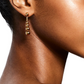 Close-up of a person wearing LIÉ STUDIO Rebecca Earrings from Lie Studio, showcasing discreet elegance with gold-plated sterling silver and a series of interconnected beads. The background is plain white.