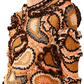 A person wears the vibrant Ulla Johnson Sunara Pullover, known for its hand-crocheted, colorful designs with intricate patterns, enhanced by wavy motifs and black, orange, and beige paisley patches.