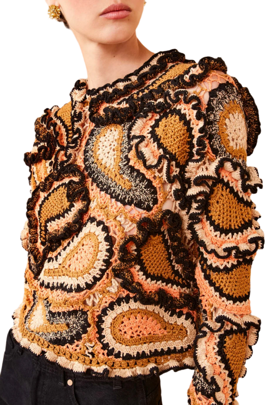 A person wears the vibrant Ulla Johnson Sunara Pullover, known for its hand-crocheted, colorful designs with intricate patterns, enhanced by wavy motifs and black, orange, and beige paisley patches.