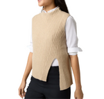 A person is wearing an Ann Mashburn Sleeveless Funnel-Neck Sweater, crafted from luxurious Mongolian cashmere in beige. This ribbed, sleeveless knit piece with a stylish slit at the side is layered over a white collared shirt and paired with black pants, creating the perfect ensemble for any layering dream.