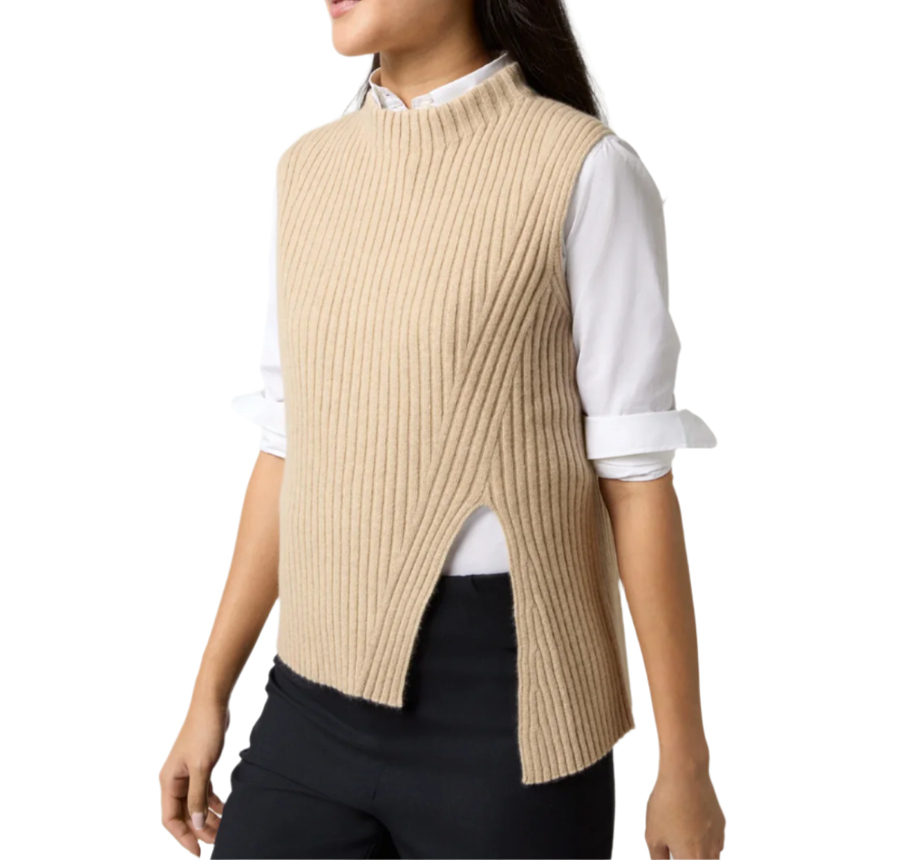 A person is wearing an Ann Mashburn Sleeveless Funnel-Neck Sweater, crafted from luxurious Mongolian cashmere in beige. This ribbed, sleeveless knit piece with a stylish slit at the side is layered over a white collared shirt and paired with black pants, creating the perfect ensemble for any layering dream.