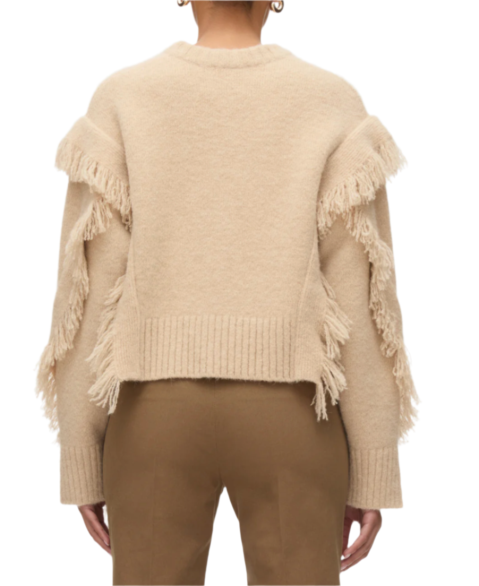 Back view of a person wearing the 3.1 Phillip Lim LS Crewneck W Fringe Trim in beige, paired with brown pants, standing against a plain background.