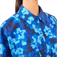 Close-up of a person wearing the Ulla Johnson Aria Blouse, highlighting its blue ikat floral pattern paired with gold earrings.