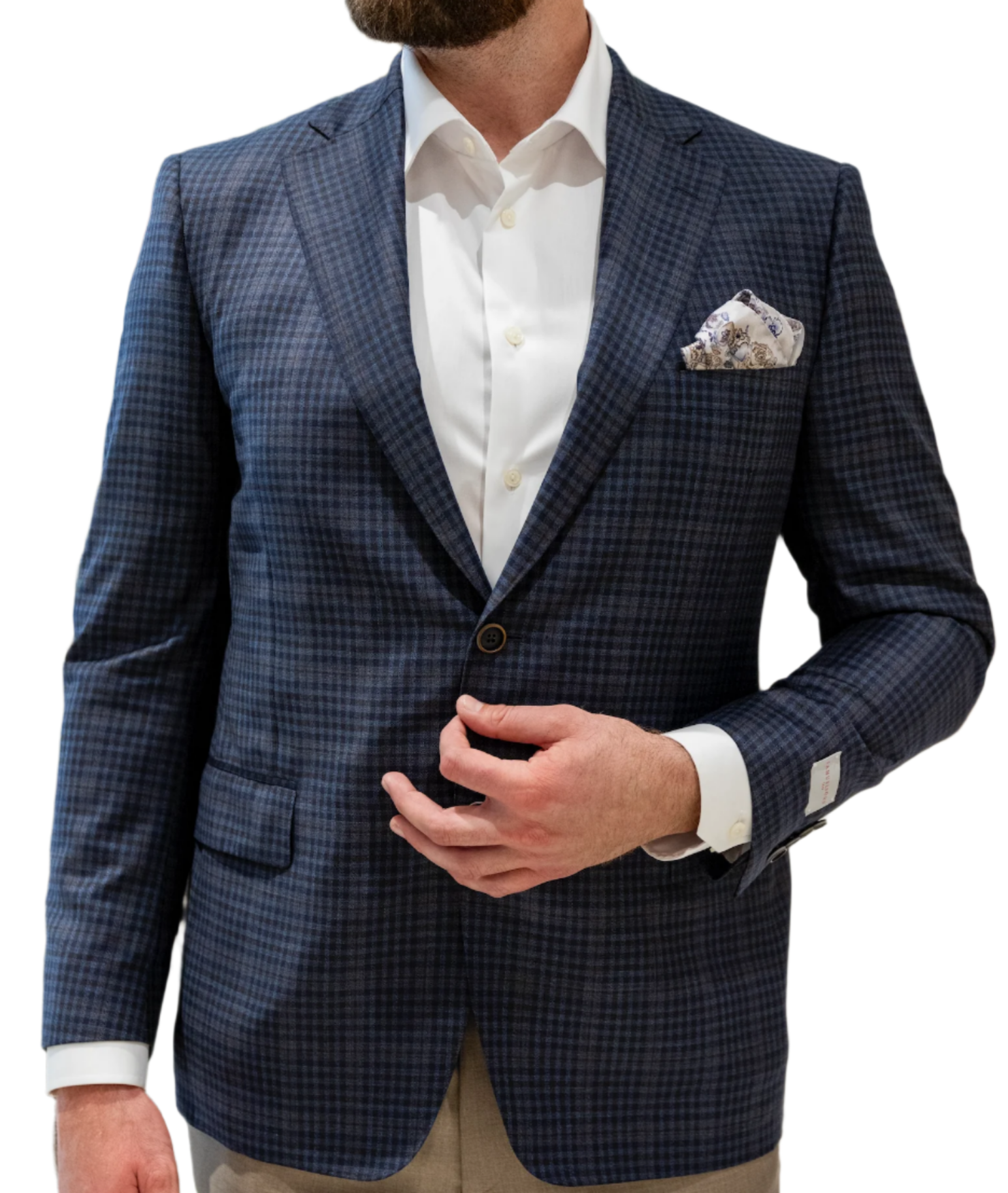 A man in a Samuelsohn Brown & Blue Even Plaid Bennet Blazer, paired with a white shirt and pocket square, adjusting his tailor-made suit crafted from luxury fabrics.