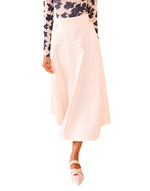 Person wearing a floral long-sleeve top, the Ulla Johnson Brigette Skirt in an elegant A-line cut, and pointed shoes.