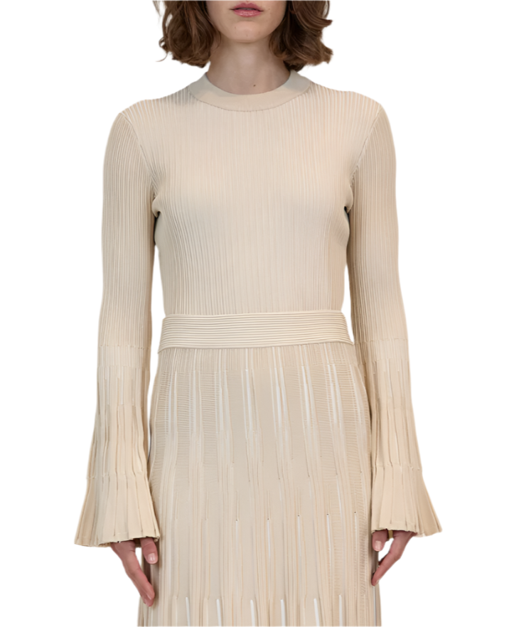 A person wearing the Simkhai Aris Top, a long-sleeved ribbed beige piece featuring flared sleeves and a matching belt.