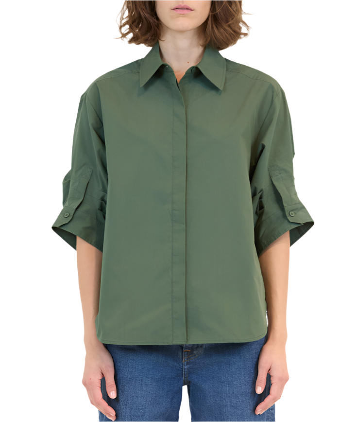 A person wearing the Simkhai Gemma Shirt, a tailored fit green button-up shirt with a classic collar and rolled sleeves, paired with blue jeans.